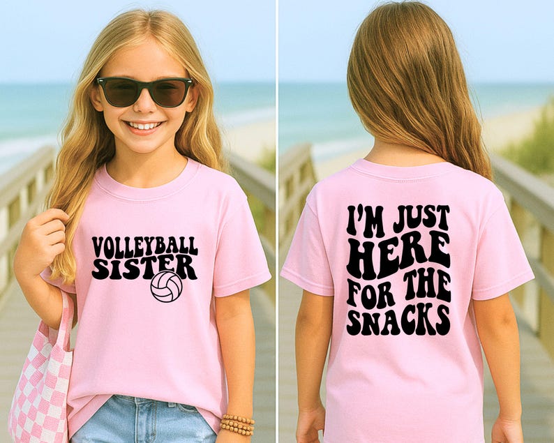 May include: A light pink t-shirt with the words "VOLLEYBALL SISTER" and a volleyball graphic. The back of the shirt says "I'M JUST HERE FOR THE SNACKS" in black text. The shirt is worn by a person with sunglasses.