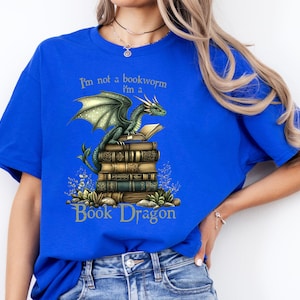 May include: A royal blue t-shirt with a green dragon sitting on a stack of books. The text on the shirt reads "I'm not a bookworm I'm a Book Dragon".
