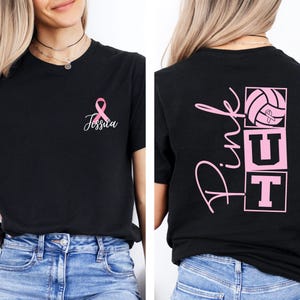 May include: Black t-shirt with a pink ribbon and the name "Jessica" in cursive. The back of the shirt features the words "Pink Out" with a volleyball and ribbon graphic. The shirt is a tribute to breast cancer awareness.