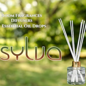 Op de afbeelding: Een heldere glazen diffuserfles met witte rietjes en een gouden deksel. De fles is gevuld met een heldere vloeistof. De tekst "ROOM FRAGRANCES DIFFUSERS ESSENTIAL OIL DROPS sylva" is zichtbaar op de achtergrond.