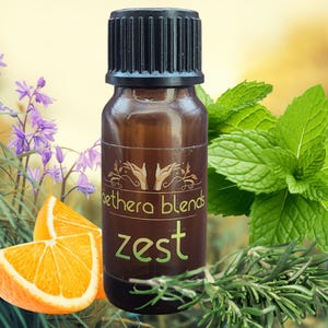 Könnte beinhalten: Eine braune Glasflasche mit schwarzem Verschluss und einem Etikett mit der Aufschrift "ethera blends zest". Die Flasche ist von Rosmarinzweigen, Minze und Orangenscheiben umgeben.