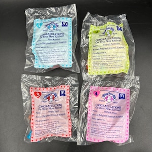 May include: Four sealed plastic bags containing Cabbage Patch Kids Happy Meal figurines. Each bag features a birth certificate design with the text Congratulations On Your New Arrival, Babyland General Hospital, and specific names for each doll.