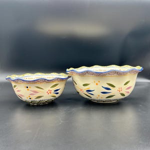 May include: A set of three ceramic mugs with a speckled, matte finish. The mugs are in shades of cream, light brown, and dark brown. Each mug has a simple, minimalist design and a rounded handle.