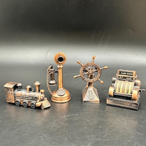 May include: A set of four miniature bronze-toned metal collectibles including a steam locomotive, an antique candlestick telephone with a chain, a ship's steering wheel on a pedestal with an anchor, and a vintage cash register labeled Cash Sales.