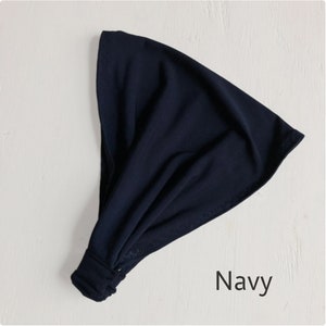 May include: A navy blue fabric headband with a knotted design. The headband is made of a soft, stretchy material.