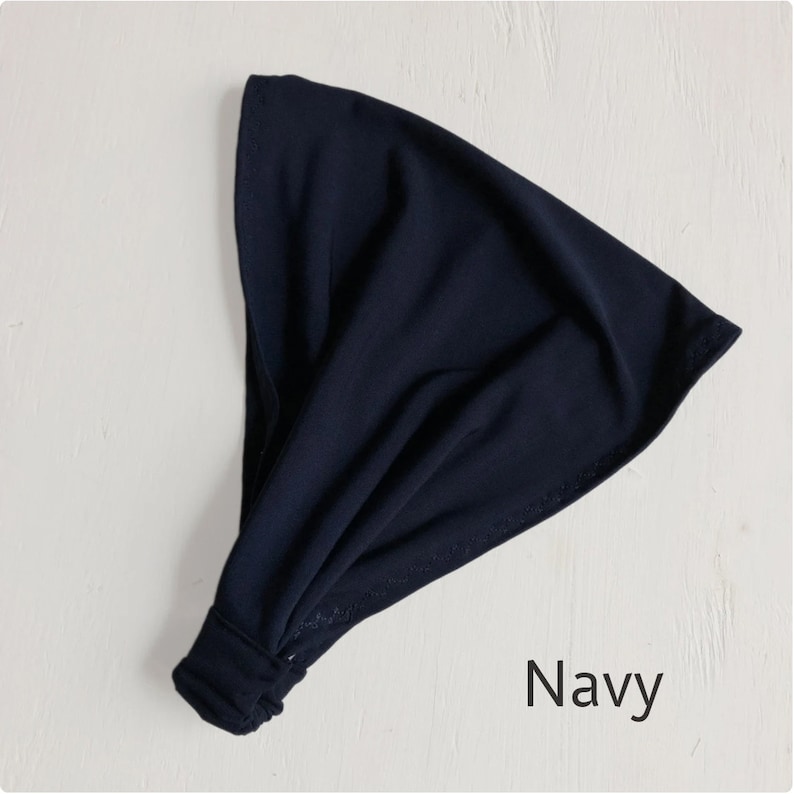 May include: A navy blue fabric headband with a knotted design. The headband is made of a soft, stretchy material.