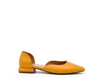 May include: A mustard yellow d'Orsay flat shoe featuring a pointed toe, a smooth leather-like finish, and a low, block-shaped heel. The design includes an open side cutout and a closed heel counter, providing a sleek and simple silhouette.