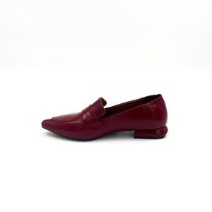 May include: A pair of burgundy leather loafers with a pointed toe and a small block heel.