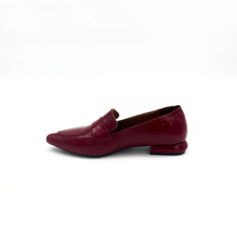 May include: A pair of burgundy leather loafers with a pointed toe and a small block heel.