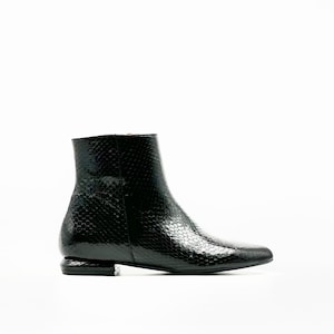 Könnte beinhalten: Schwarzer Stiefelette mit strukturierter, schlangenlederartiger Musterung. Der Schuh hat einen niedrigen Absatz und eine spitze Zehenpartie. Der Schuh ist aus glänzendem Material gefertigt und hat einen Reißverschluss an der Seite.
