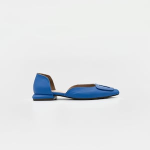 May include: A pair of blue leather flats with a cut-out detail and a buckle accent.