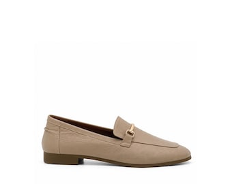 May include: A beige leather loafer featuring a smooth, rounded toe and a low, flat heel. The shoe is accented with a polished gold-tone metal bit detail across the vamp, providing a clean, structured look with a dark brown sole.