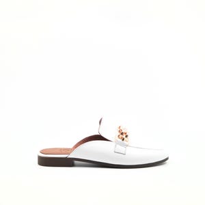 Könnte beinhalten: Weißer Leder-Slipper mit goldenem Kettendetail. Der Schuh hat eine braune Sohle und einen niedrigen Absatz. Das Design ist minimalistisch und elegant, passend für verschiedene Anlässe.