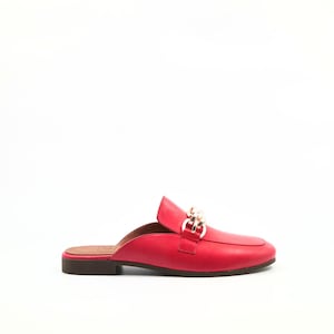 May include: A red leather mule with a gold-colored chain detail across the vamp. The shoe has a rounded toe and a low heel. The sole is brown.