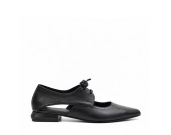 May include: A black leather flat shoe with a pointed toe, a lace-up front closure, and a distinctive side cutout design. The shoe features a low, structured block heel and a smooth finish, showcasing a sleek silhouette with visible stitching details.
