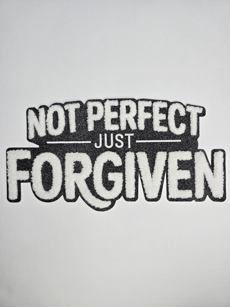 May include: A black and white patch with the words "NOT PERFECT" above "JUST" and "FORGIVEN" in a bold, textured font. The patch has a black border and is set against a white background.