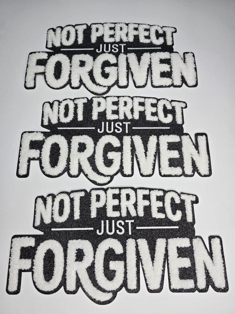May include: Three black and white patches with the text "NOT PERFECT JUST FORGIVEN". The text is in a bold, stylized font with a fuzzy, textured appearance. The patches are rectangular with rounded corners.