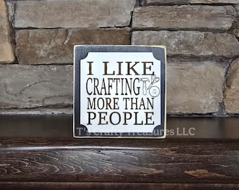 May include: A black and white wooden sign with the text "I like crafting more than people" and a graphic of tools.