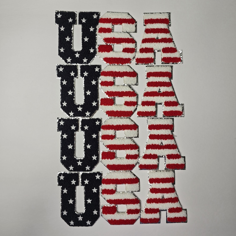 May include: Four sets of USA letter patches. The letter U is navy blue with white stars. The letters S and A have red and white stripes. The patches have a silver border.