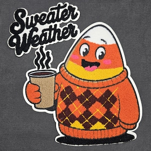 Peut inclure: Un écusson représentant un bonbon en forme d'épi de maïs portant un pull orange à motif losanges marron, tenant une tasse de café. Le texte "Sweater Weather" est au-dessus du bonbon. Le fond est gris uni.