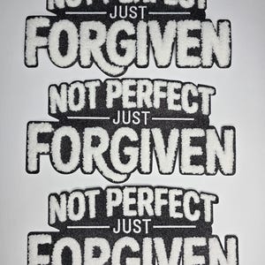May include: Three black and white patches with the text "NOT PERFECT - JUST - FORGIVEN". The text is in a bold, stylized font with a fuzzy, white texture, set against a black background. The patches are arranged vertically.