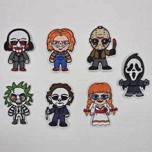 May include: Seven embroidered patches showcasing cartoon horror characters. The patches feature characters such as Jigsaw, Chucky, Jason Voorhees, and Beetlejuice. Each patch has unique colours and designs. These patches are suitable for decorating clothing or accessories.