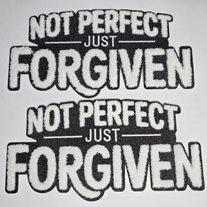 May include: Two black and white patches with the words "NOT PERFECT" above "JUST" and "FORGIVEN". The text is in a bold, stylized font with a fuzzy, textured appearance. The patches are on a white background.