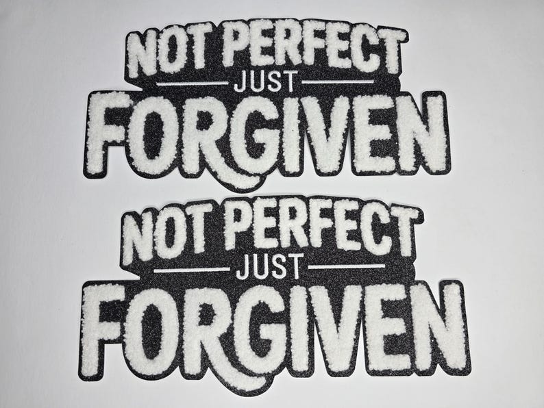May include: Two black and white patches with the words "NOT PERFECT" above "JUST" and "FORGIVEN". The text is in a bold, stylized font with a fuzzy, textured appearance. The patches are on a white background.