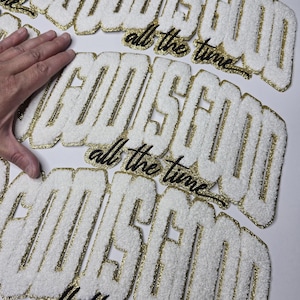 May include: White, textured patches with gold trim and the words "GOOSED" and "all the time" in black script. The patches are arranged on a white surface.
