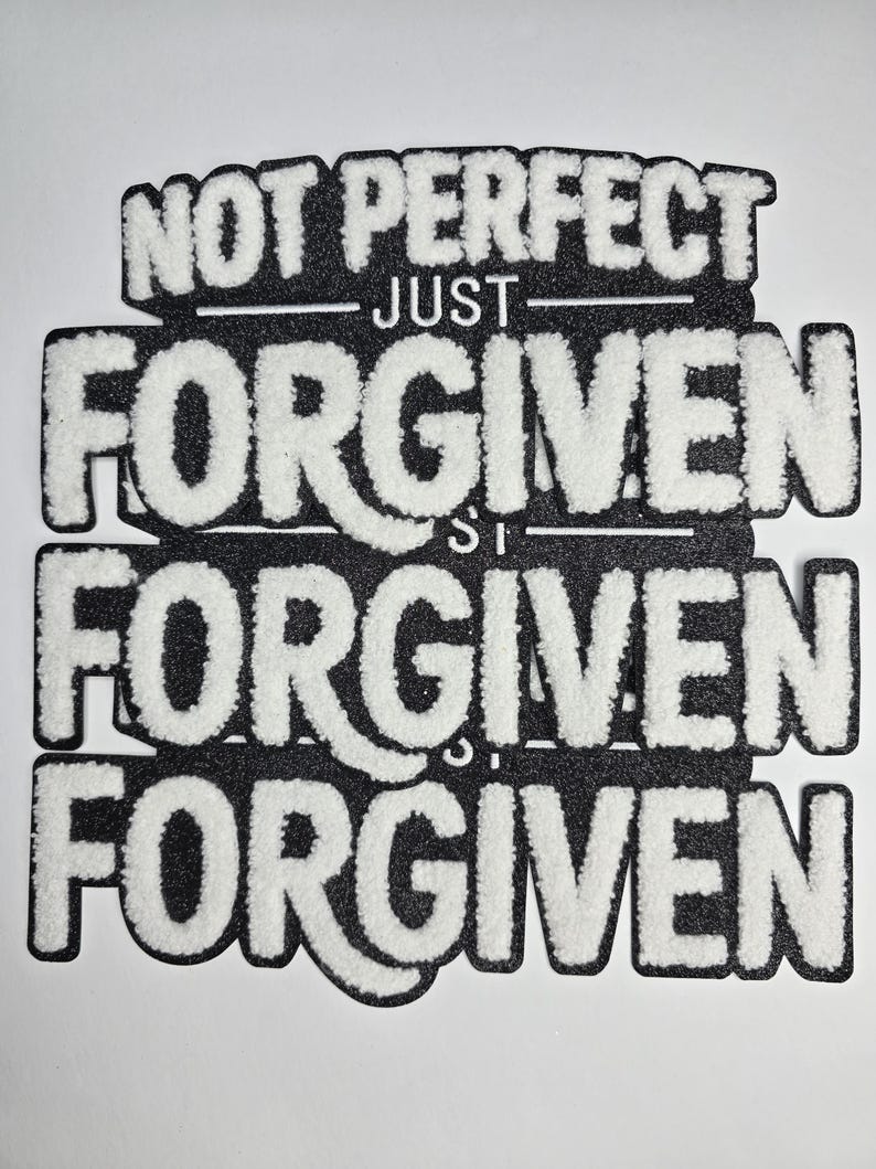 May include: A black and white patch with the words "NOT PERFECT JUST FORGIVEN" in a layered design. The text is in a bold, textured font, with white lettering on a black background. The patch is likely for clothing or accessories.