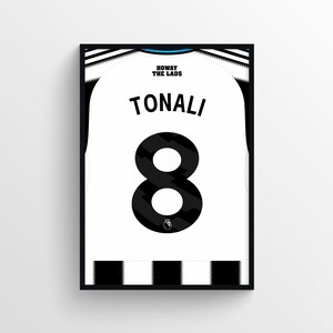 May include: Framed print of a white and black soccer jersey. The jersey features the name "TONALI" and the number "8" in black. The text "HOWAY THE LADS" is above the name. The Premier League logo is at the bottom.