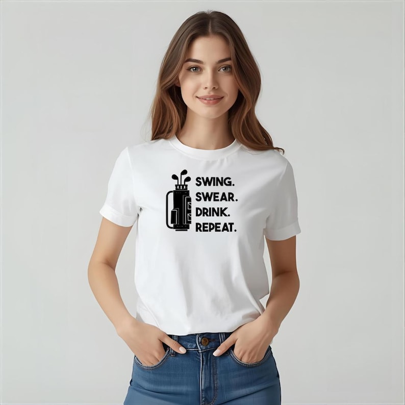 May include: White t-shirt with a black graphic of a golf bag and clubs, and the text "SWING. SWEAR. DRINK. REPEAT." The shirt has short sleeves and a crew neck.