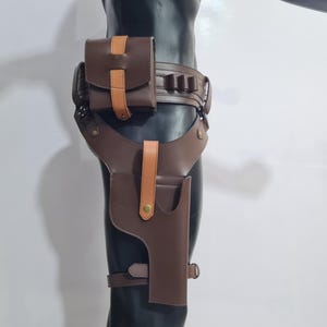 Puede incluir: Funda de muslo de cuero marr&oacute;n con cintur&oacute;n y bolsa a juego. La funda tiene un bolsillo para pistola y una correa que se asegura alrededor del muslo. El cintur&oacute;n tiene m&uacute;ltiples presillas y una bolsa con un acento marr&oacute;n claro.