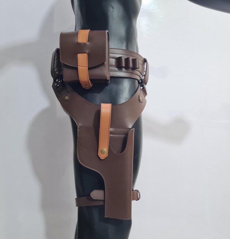 Puede incluir: Funda de muslo de cuero marr&oacute;n con cintur&oacute;n y bolsa a juego. La funda tiene un bolsillo para pistola y una correa que se asegura alrededor del muslo. El cintur&oacute;n tiene m&uacute;ltiples presillas y una bolsa con un acento marr&oacute;n claro.