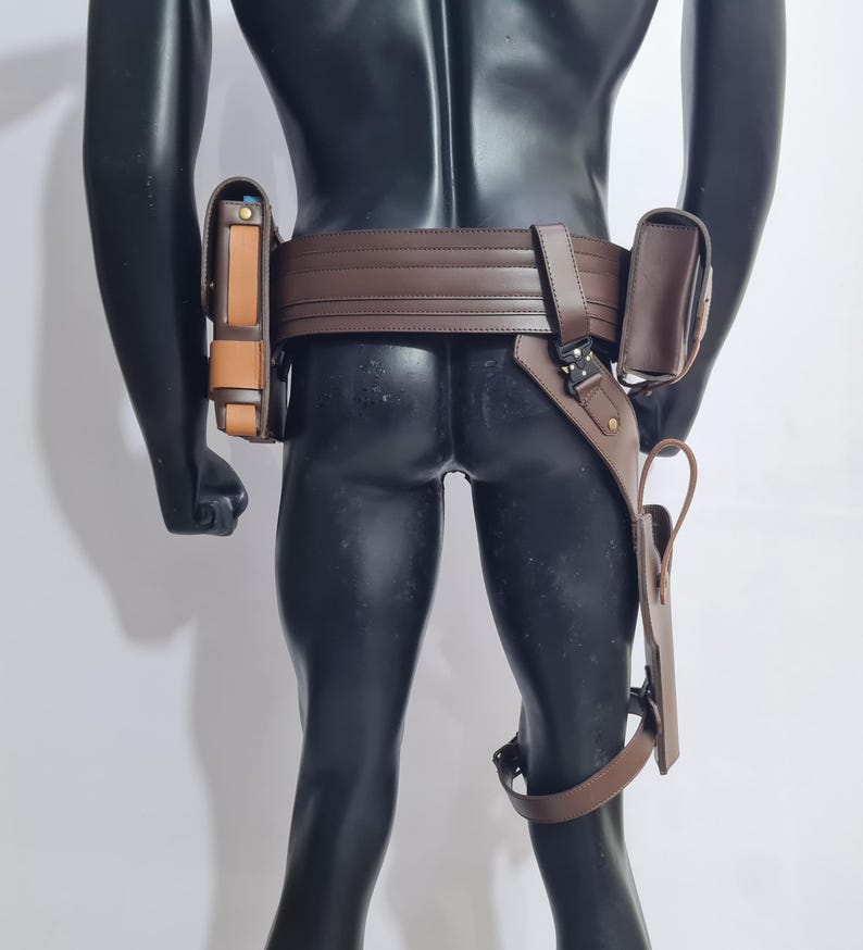 Puede incluir: Un cintur&oacute;n utilitario de cuero marr&oacute;n con m&uacute;ltiples bolsas y una funda para la pierna. El cintur&oacute;n se lleva alrededor de la cintura y tiene un cierre de hebilla. Las bolsas son de varios tama&ntilde;os y formas, y la funda para la pierna est&aacute; sujeta con una correa.