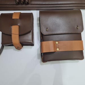 Puede incluir: Dos bolsas de cuero marr&oacute;n con correas de cuero color canela y herrajes de lat&oacute;n. Una bolsa es cuadrada con una solapa y una correa vertical. La otra es rectangular con una correa horizontal. Se ve un cintur&oacute;n a juego.