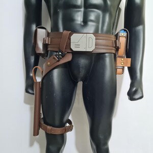 Puede incluir: Cintur&oacute;n utilitario de cuero marr&oacute;n con m&uacute;ltiples bolsillos y una funda. El cintur&oacute;n presenta una hebilla plateada y una correa para el muslo. Los accesorios est&aacute;n sujetos al cintur&oacute;n con correas y hebillas de cuero. El cintur&oacute;n se muestra en un maniqu&iacute; negro.