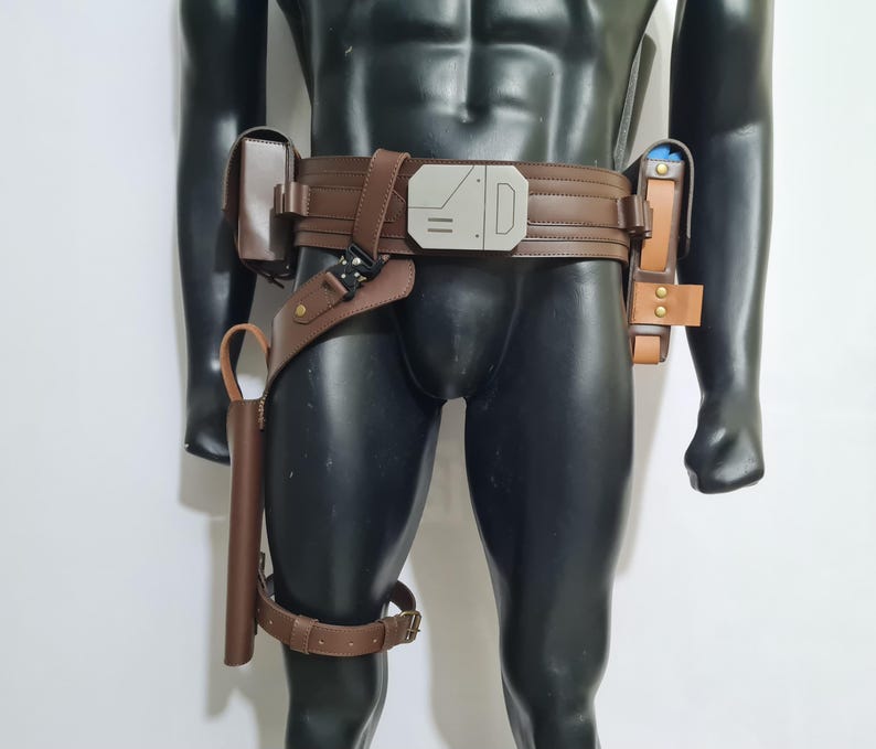 Puede incluir: Cintur&oacute;n utilitario de cuero marr&oacute;n con m&uacute;ltiples bolsillos y una funda. El cintur&oacute;n presenta una hebilla plateada y una correa para el muslo. Los accesorios est&aacute;n sujetos al cintur&oacute;n con correas y hebillas de cuero. El cintur&oacute;n se muestra en un maniqu&iacute; negro.