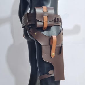 Puede incluir: Juego de cintur&oacute;n y funda de cuero marr&oacute;n. El conjunto incluye un cintur&oacute;n con una bolsa y portacartuchos, y una funda para la pierna. El cuero es de un marr&oacute;n intenso con detalles en beige.
