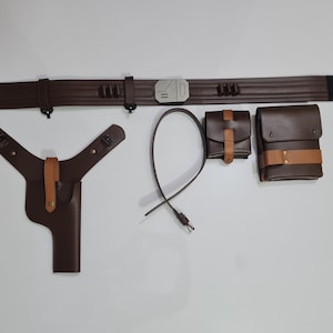 Puede incluir: Un cintur&oacute;n de cuero marr&oacute;n con hebilla plateada, una funda, dos bolsas y una correa. El cintur&oacute;n tiene una secci&oacute;n negra en un extremo. La funda y las bolsas tienen detalles en color canela.