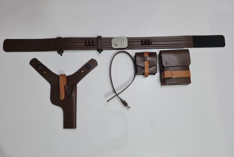 Puede incluir: Un cintur&oacute;n de cuero marr&oacute;n con hebilla plateada, una funda, dos bolsas y una correa. El cintur&oacute;n tiene una secci&oacute;n negra en un extremo. La funda y las bolsas tienen detalles en color canela.