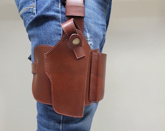 May include: Brown leather holster with a black buckle and brown leather straps. The holster is attached to a person's leg, and is designed to hold a firearm. The holster is made of a sturdy material and is designed for durability.