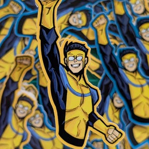 May include: A collection of stickers featuring a comic book superhero in a yellow and blue costume. The character is depicted with a raised fist and a confident expression, with black hair and glasses. The stickers are on a white background.