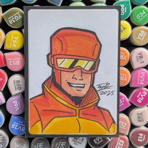 May include: A rectangular drawing of a character wearing an orange helmet and yellow-tinted goggles, dressed in an orange and yellow jacket. The artwork features bold black outlines, a smiling expression, and the signature and date 2025 in black ink.