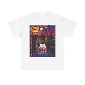 Può includere: T-shirt bianca con grafica di Dikembe Mutombo dalla rivista SLAM. L'immagine mostra Mutombo in azione, con il logo della rivista e il testo "MOUNTAIN CLIMBING" e "DIKEMBE MUTOMBO" visibili. La maglietta elenca anche altri giocatori di basket.