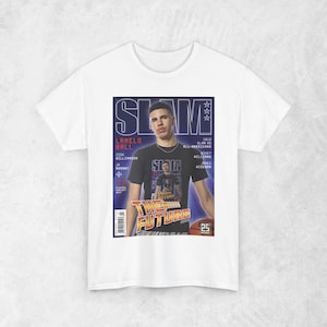 以下が含まれることがあります： 雑誌の表紙デザインが施された白いTシャツ。「SLAM」の文字、「LAMELO BALL」、「THE FUTURE」の文字が大きく表示されています。バスケットボールも描かれています。デザインは主に青、黒、白です。