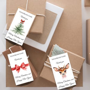 Puede incluir: Etiquetas de regalo con ilustraciones de acuarela de un &aacute;rbol de Navidad, un lazo rojo y un ciervo. Cada etiqueta tiene el texto "YOUR BRAND NAME", "Wish you" y "Merry Christmas and Happy New Year!". Los regalos est&aacute;n envueltos en papel marr&oacute;n.