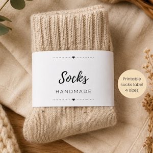 May include: A pair of beige handmade socks with a white label that reads "Socks Handmade". The socks are folded and wrapped with a white label. A round sticker says "Printable socks label 4 sizes".