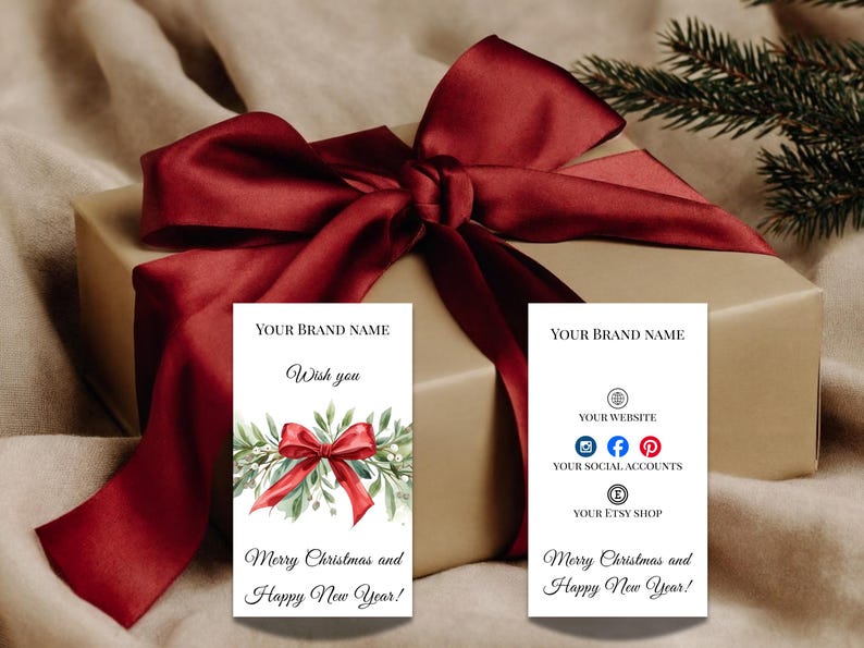 Puede incluir: Un regalo envuelto con un gran lazo de sat&eacute;n burdeos. Se ven dos tarjetas blancas, una con un lazo y vegetaci&oacute;n de acuarela, la otra con iconos de redes sociales. El texto de las tarjetas dice "&iexcl;Feliz Navidad y Pr&oacute;spero A&ntilde;o Nuevo!"