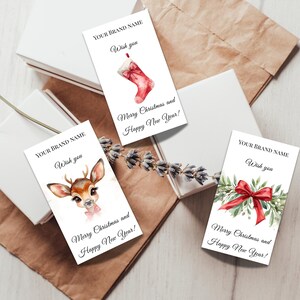 Puede incluir: Etiquetas de regalo navide&ntilde;as con ilustraciones de acuarela de un calcet&iacute;n navide&ntilde;o, un ciervo y una ramita con un lazo rojo. Cada etiqueta tiene el texto "YOUR BRAND NAME" y "Wish you", con "Merry Christmas and Happy New Year!" debajo.